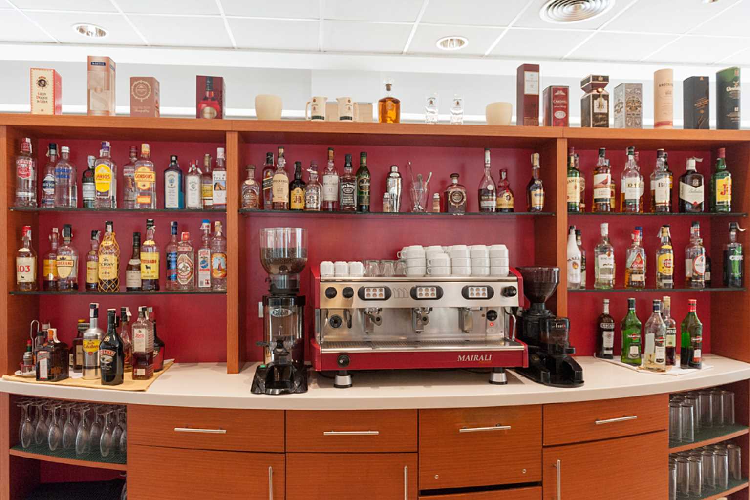 Cafeteria shelf with coffee machine, coffee grinders and bottle of alcohol of all kinds: brandy, whiskey, beilis, gin, martini, rum, liqueurs...